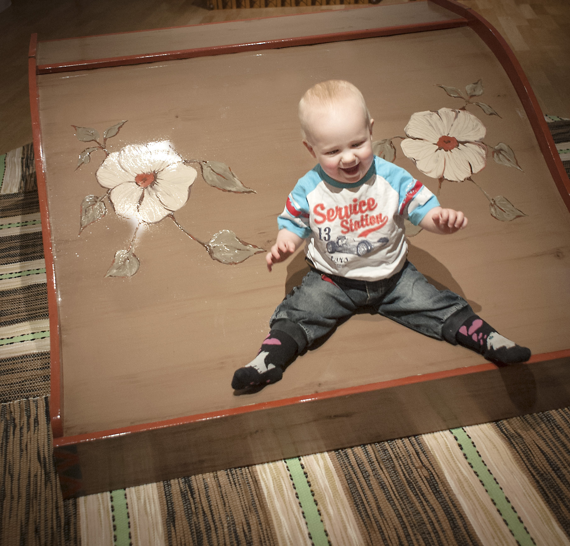 'Liten glad tjej som åker rutschkanan i utställningen Kan själv. Under rutschkanan ligger två trasmattor på golvet.'